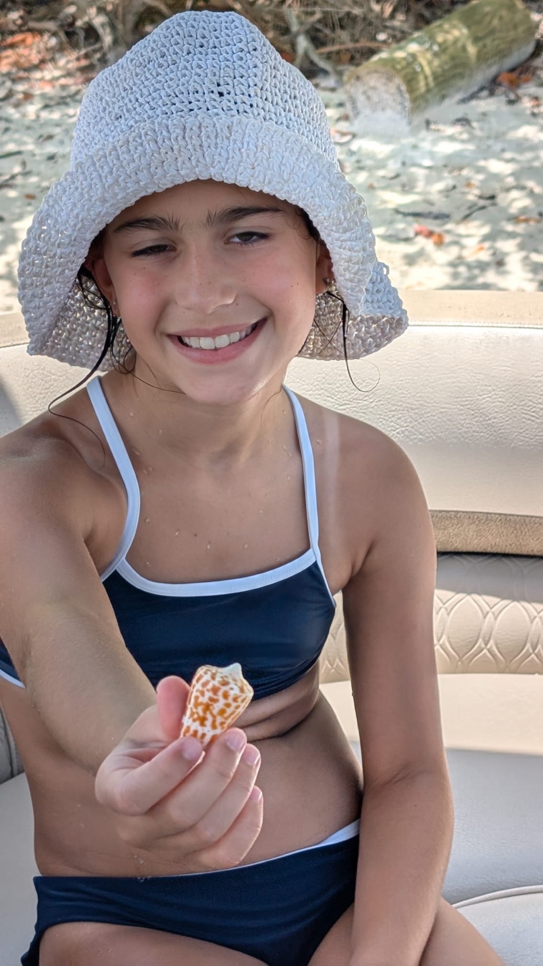 A young girl on a Sand Dollar Shelling boat holding up a beautiful spotted Junonia shell